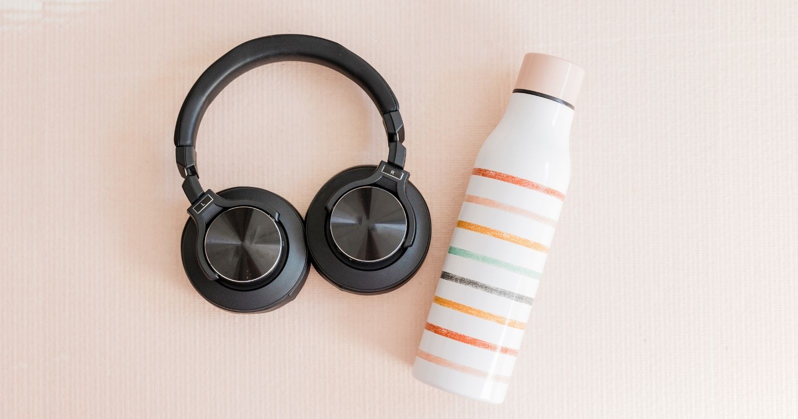 striped water bottle with headphones on pink background