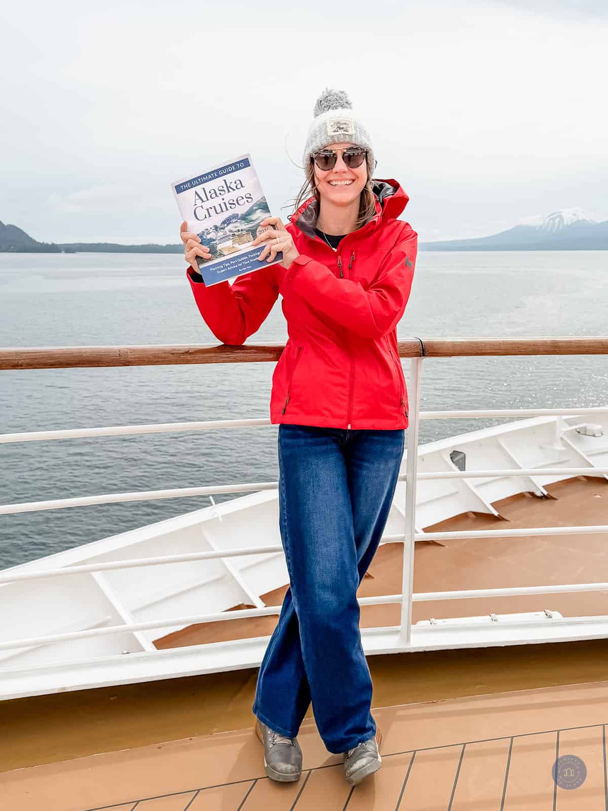 Woman holding Alaska cruise guide book on boat deck.