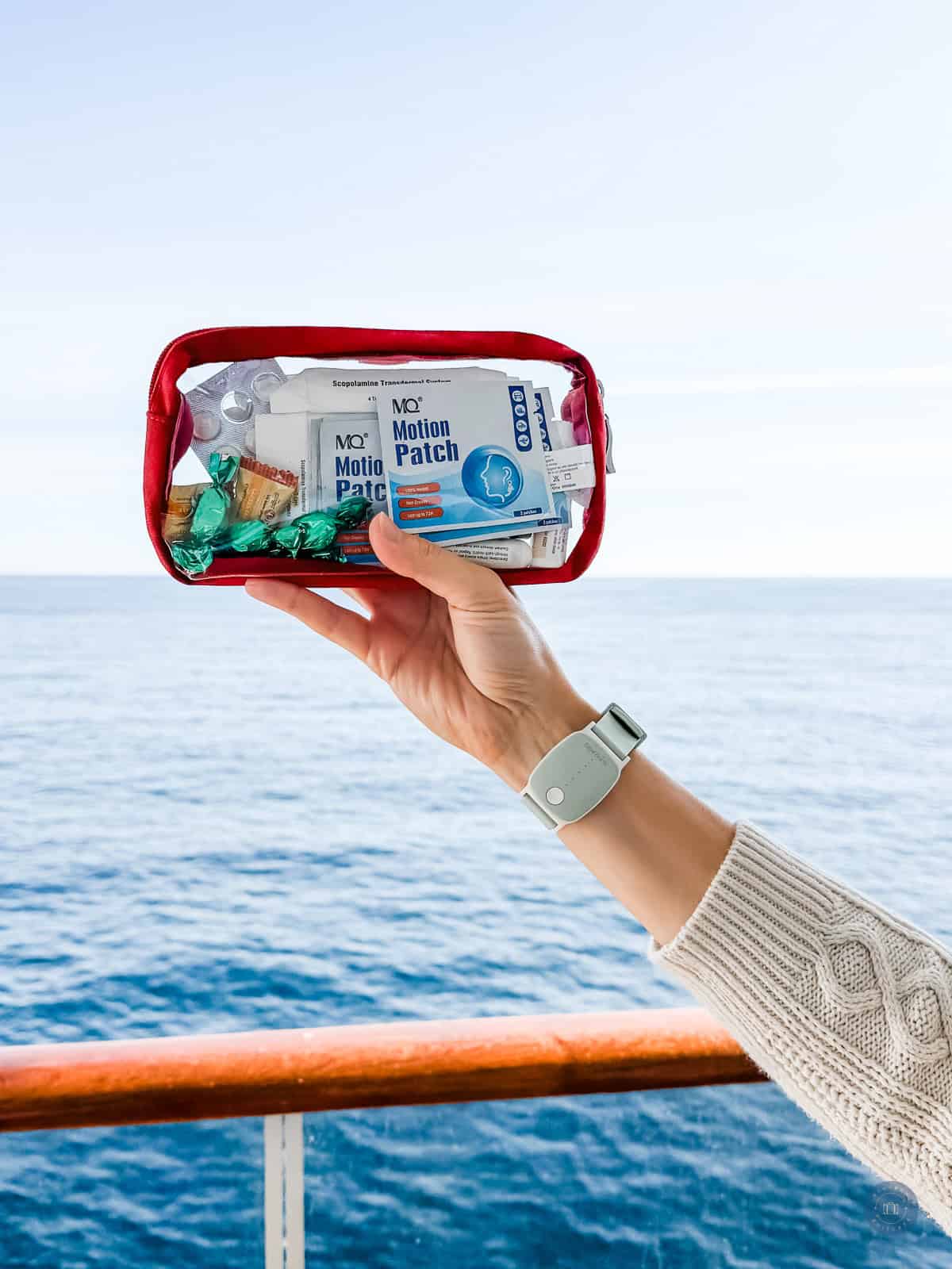 Hand holding a travel first aid kit with motion sickness patches on a cruise ship.