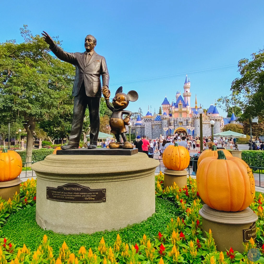 partners statue at disneyland with pumpkins and castle