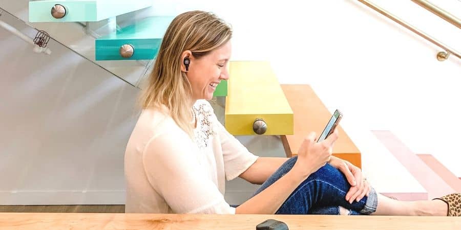 girl on phone wearing earbuds in store