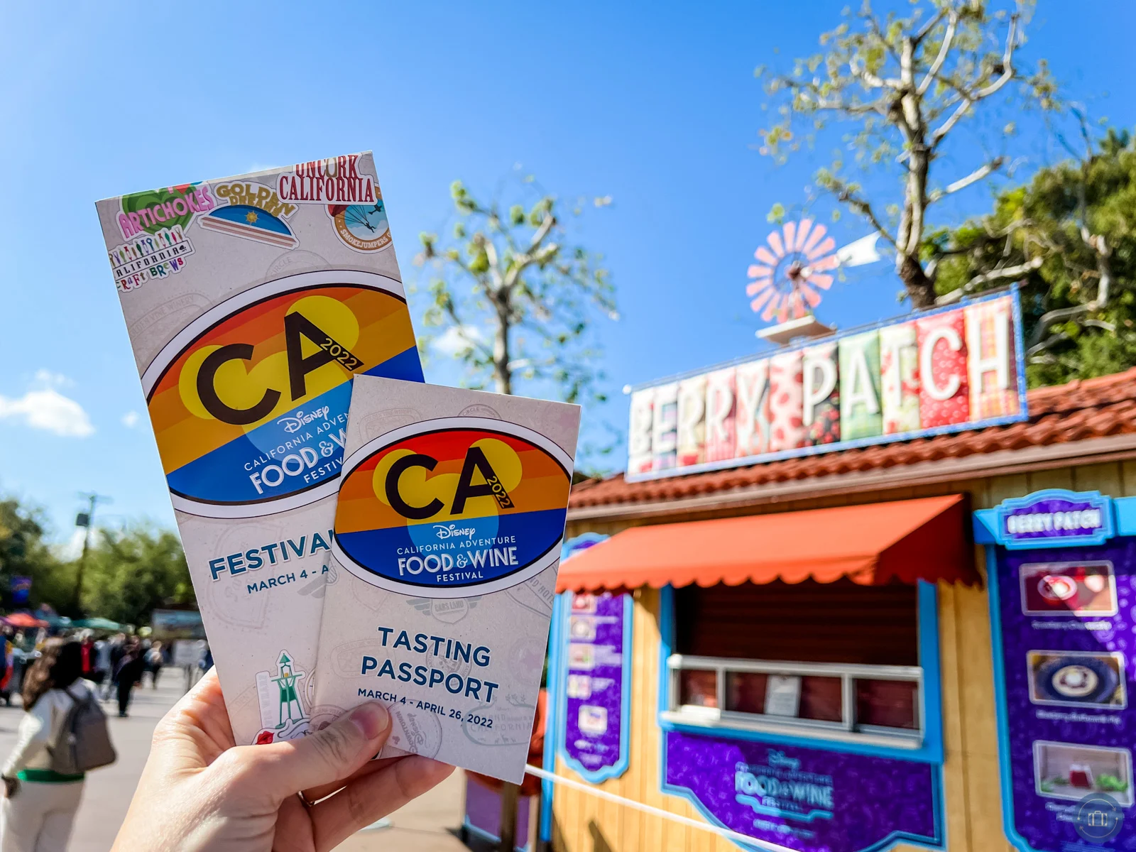 2022 disneyland food and wine festival brochures held in front of festival marketplace booth