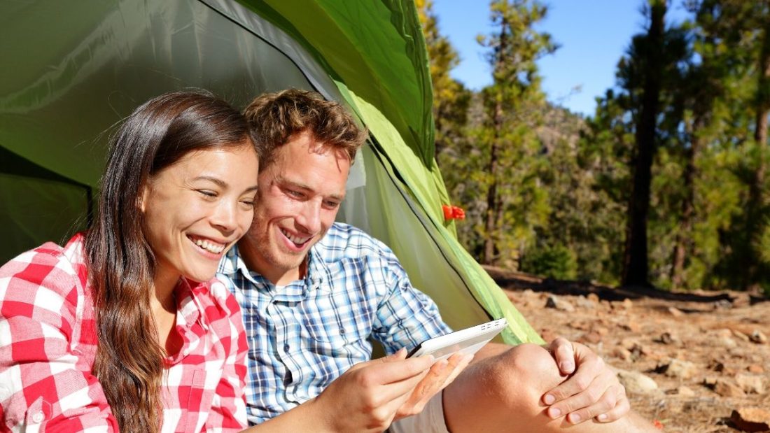 couple on phone camping in tent
