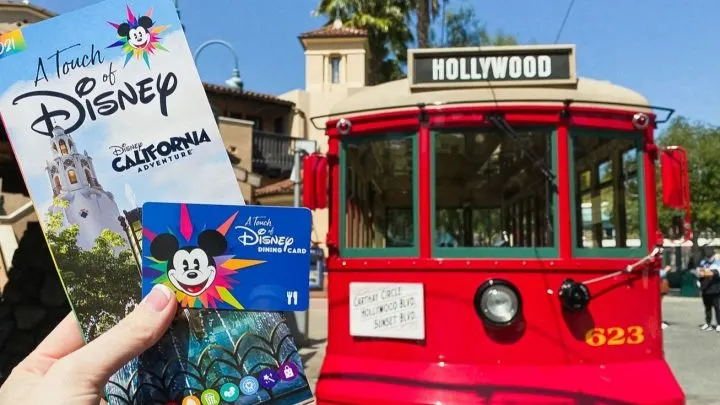 holding touch of disney park map and dining card in front of red trolley at Disney California Adventure Disneyland