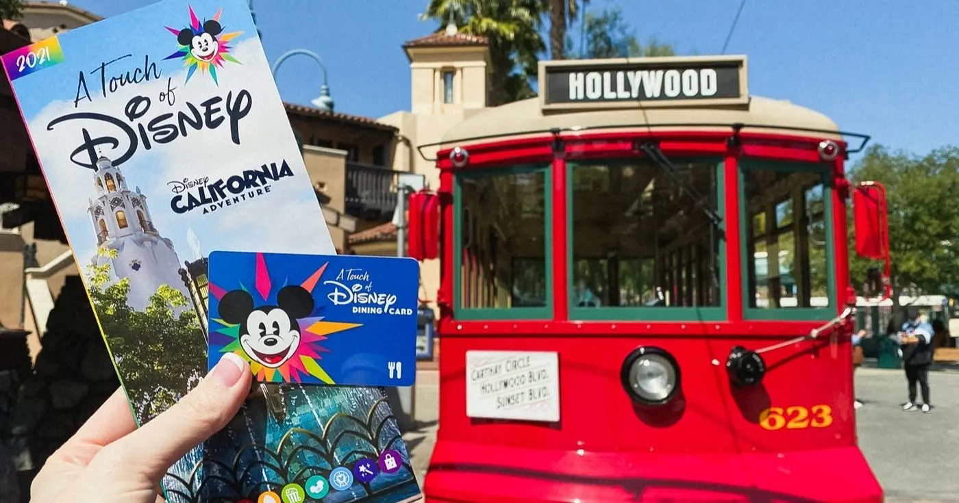 holding touch of disney park map and dining card in front of red trolley at Disney California Adventure Disneyland