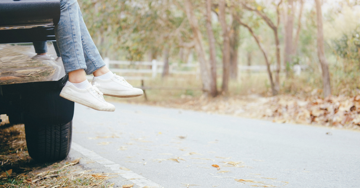 girl wearing tennis shoes sitting in back of car on road trip