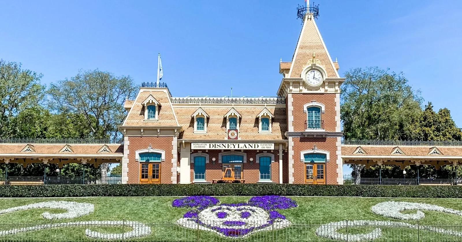 disneyland railroad at park entrance with mickey head floral design in front