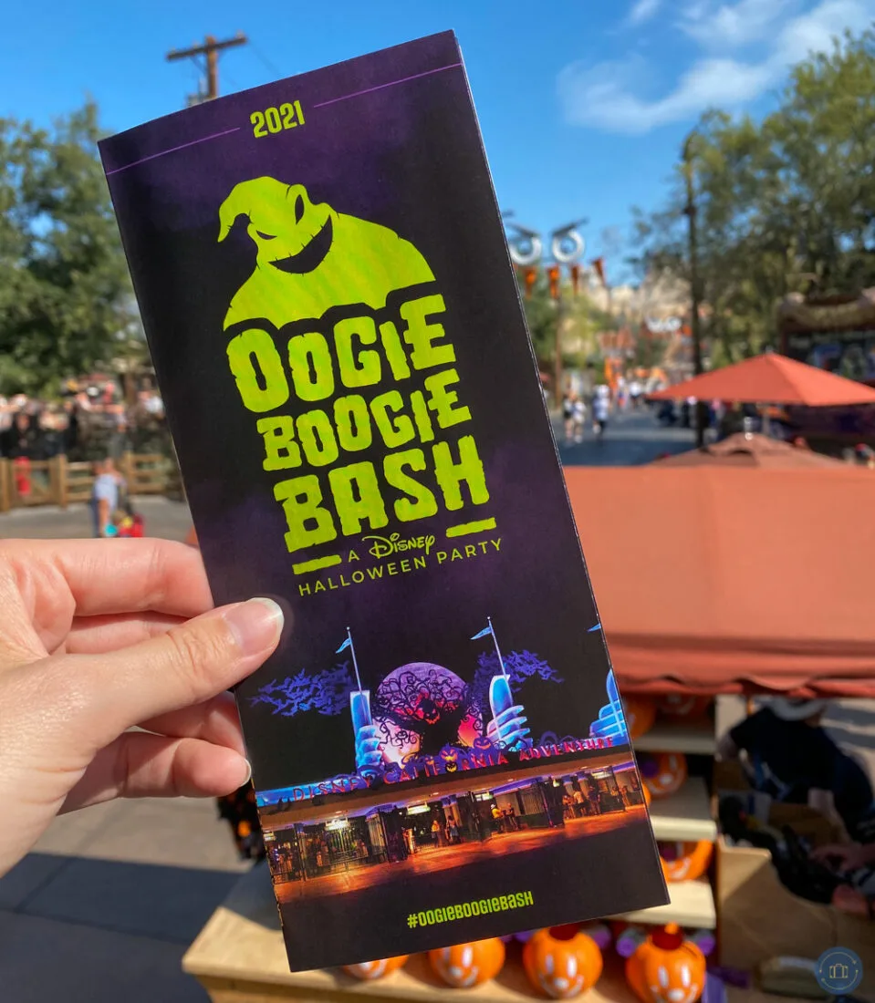 hand holding pamphlet for 2021 oogie boogie bash halloween party at disneyland