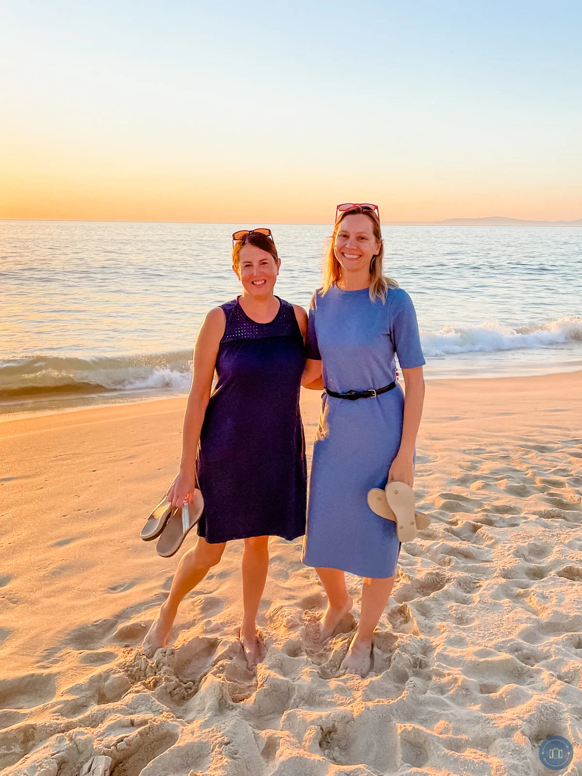two women wearing dresses on portugal beach at sunset
