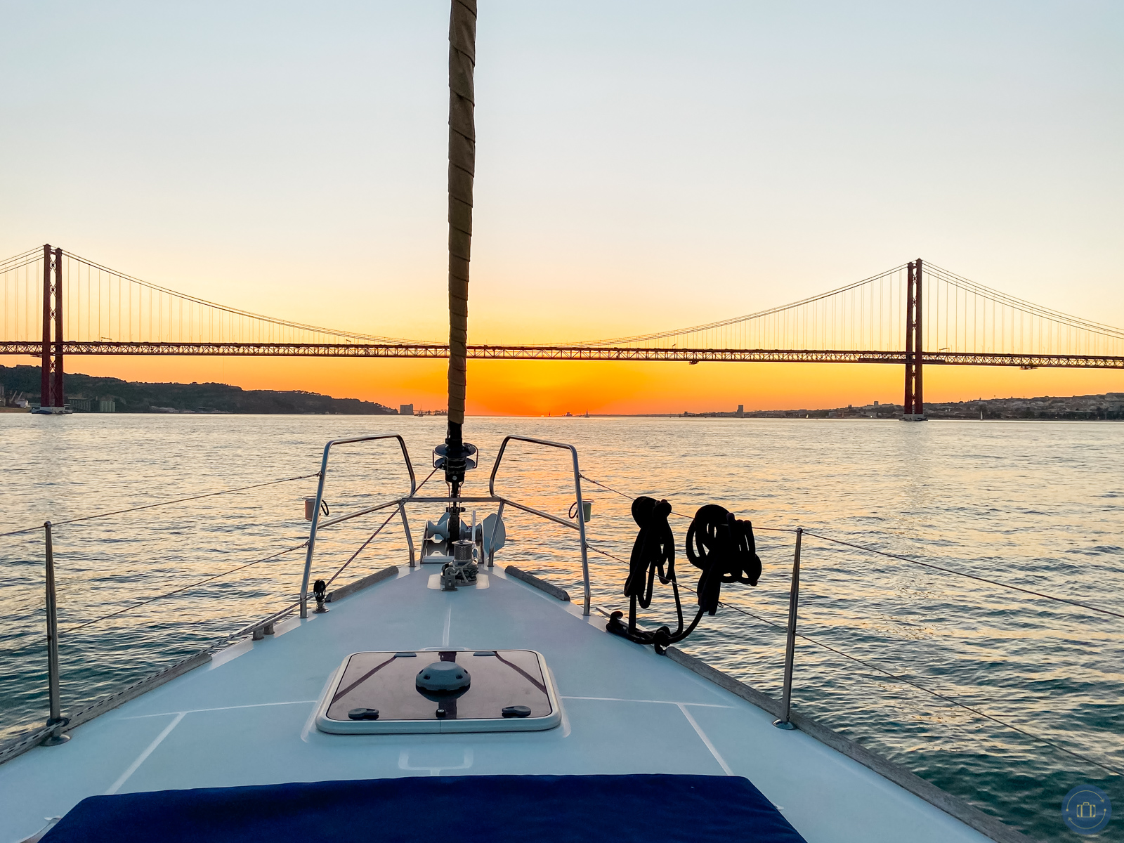 beautiful sunset view from sailboat looking at 25 de Abril Bridge on Tagus River in Belem Portugal city