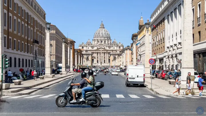 view of basilica in rome italy from end of street with scooter driving by road
