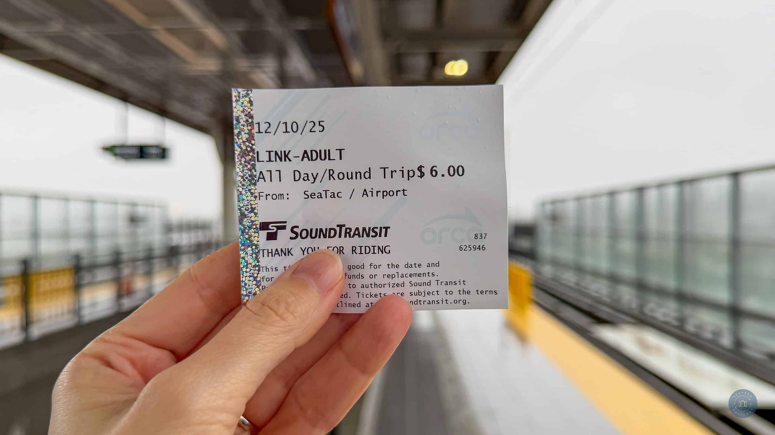 person holding sound transit link light rail ticket at seattle airport light rail train station platform