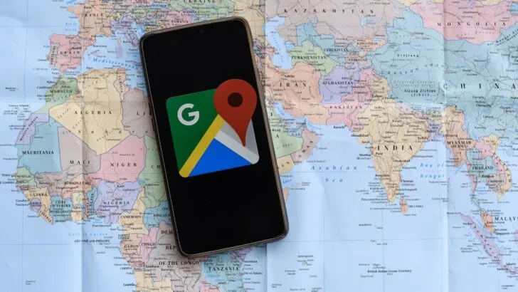 phone with google maps logo sitting on top of paper world map