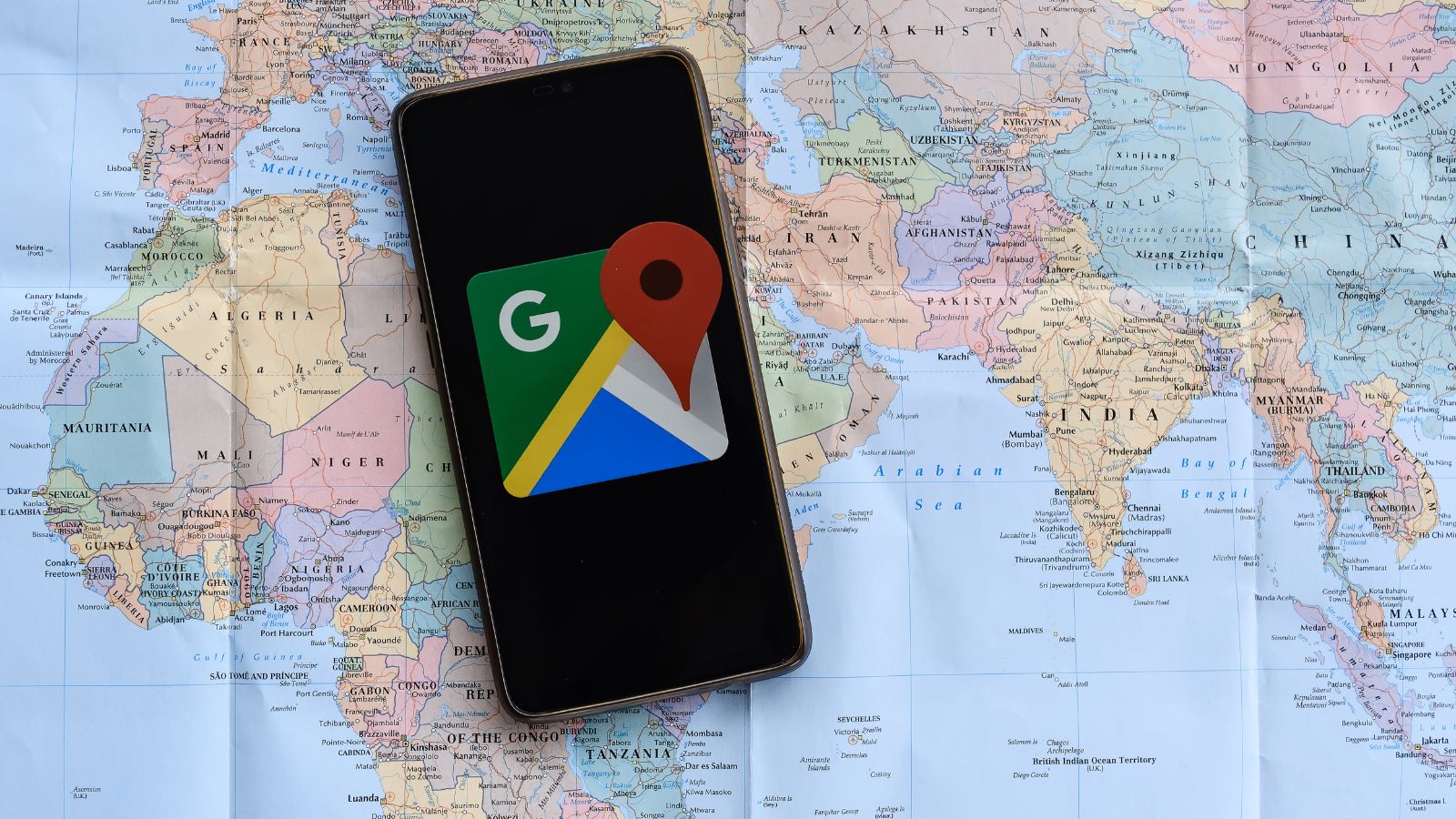 A map with smart phone laying on it with Google Maps open.