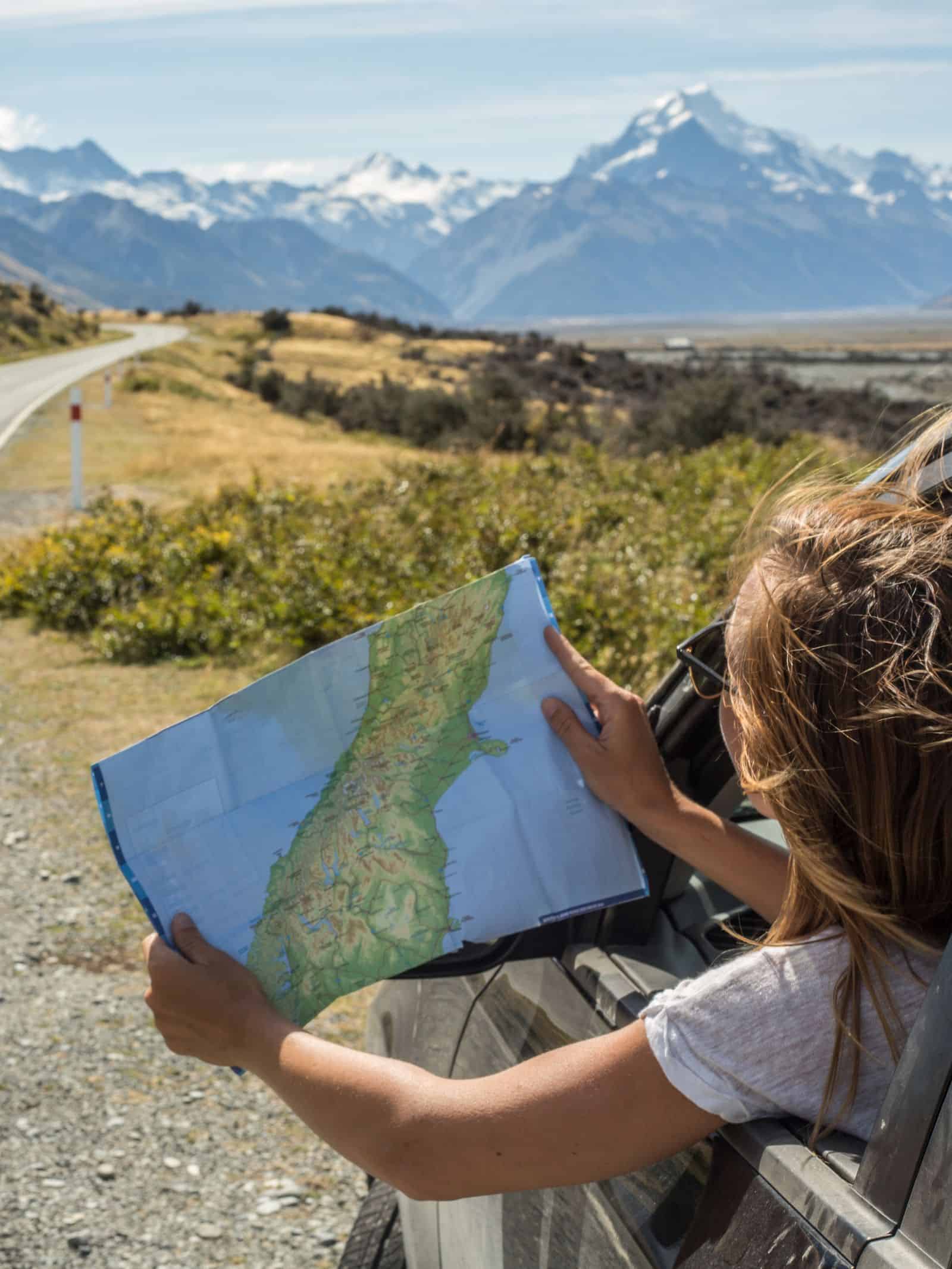 Woman looking at map out of the car window.