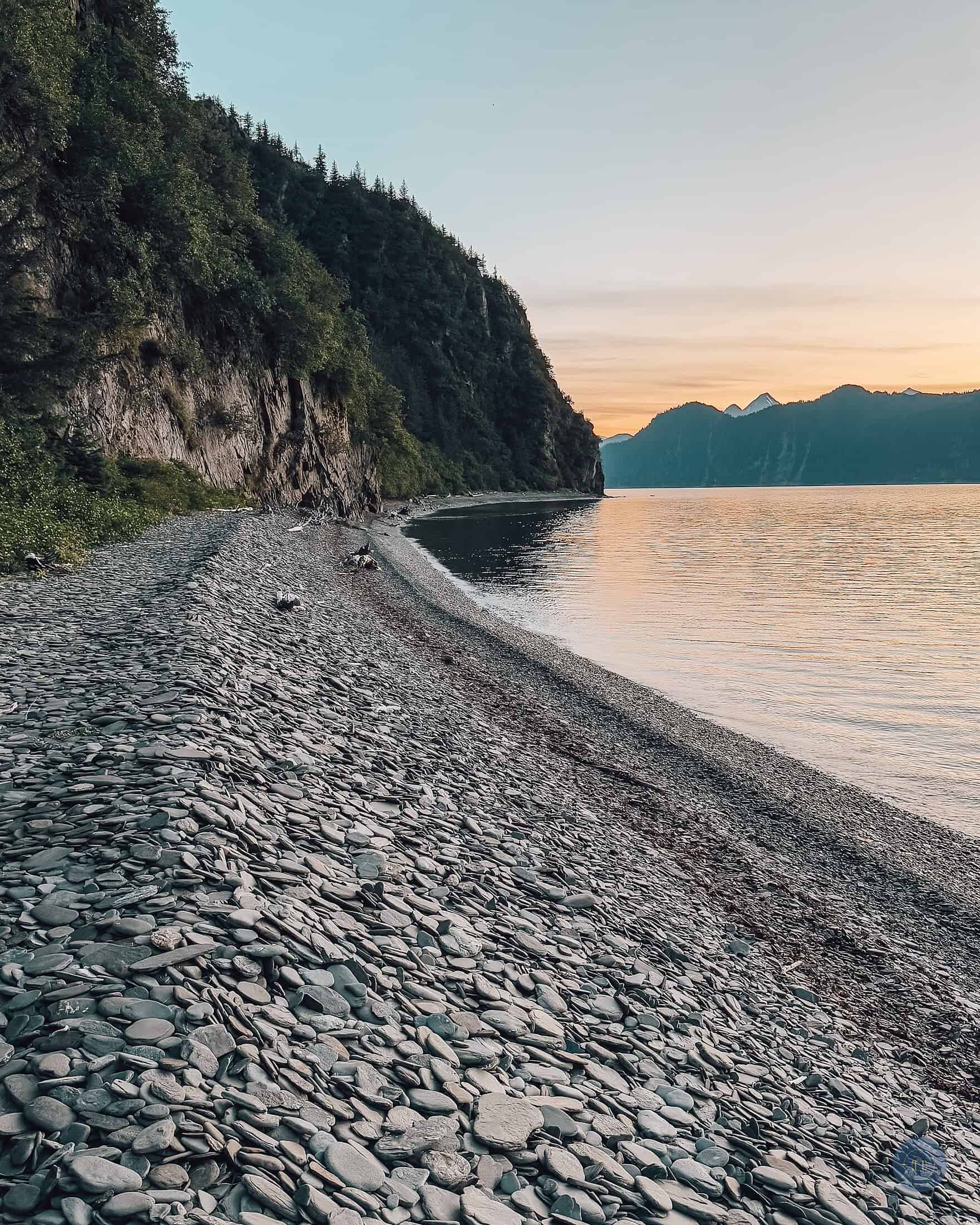 A beach walk on Fox Island Alaska with rocks and water at sunset.
