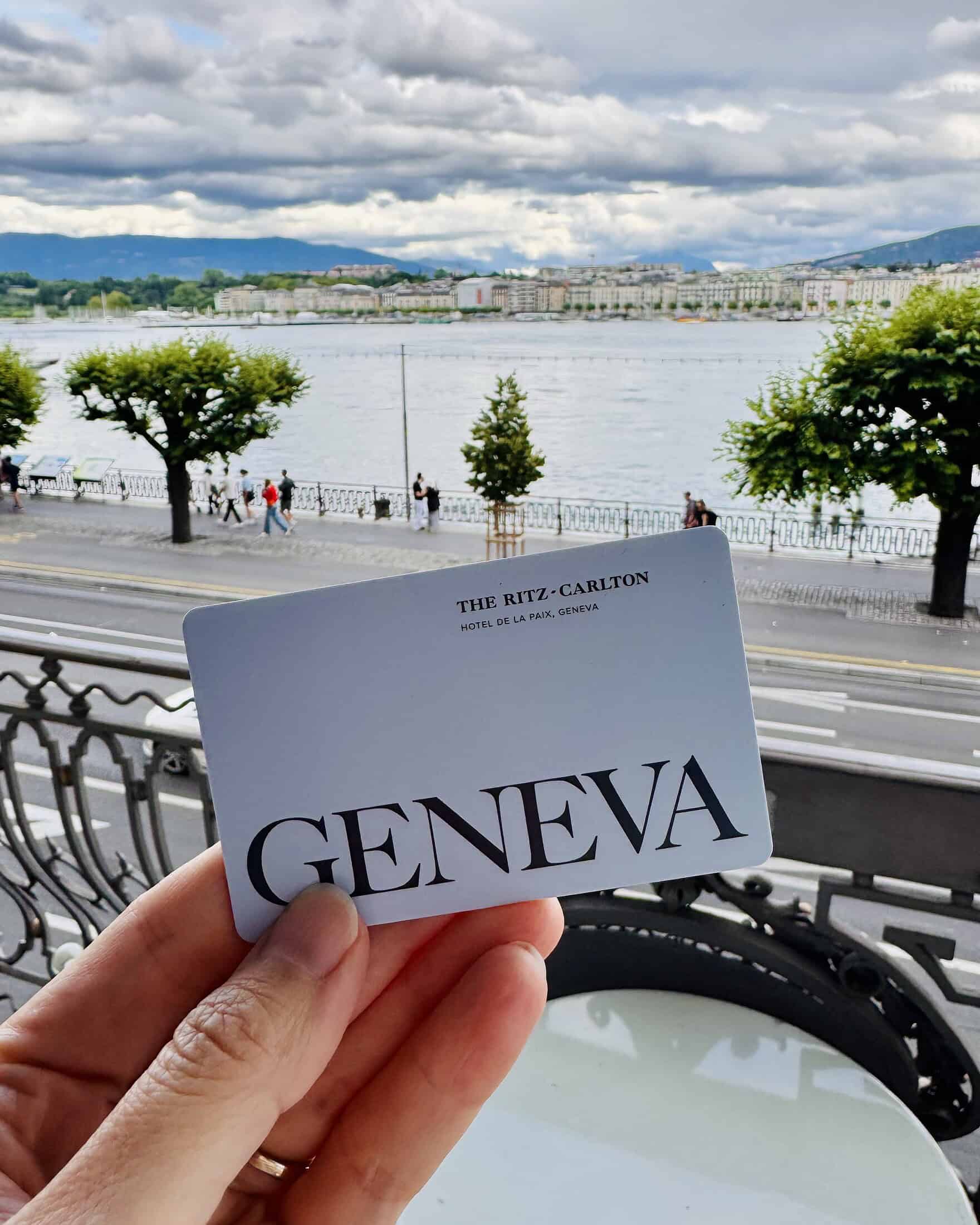 holding a ritz carlton geneva hotel key on balcony of hotel looking at lake geneva in switzerland