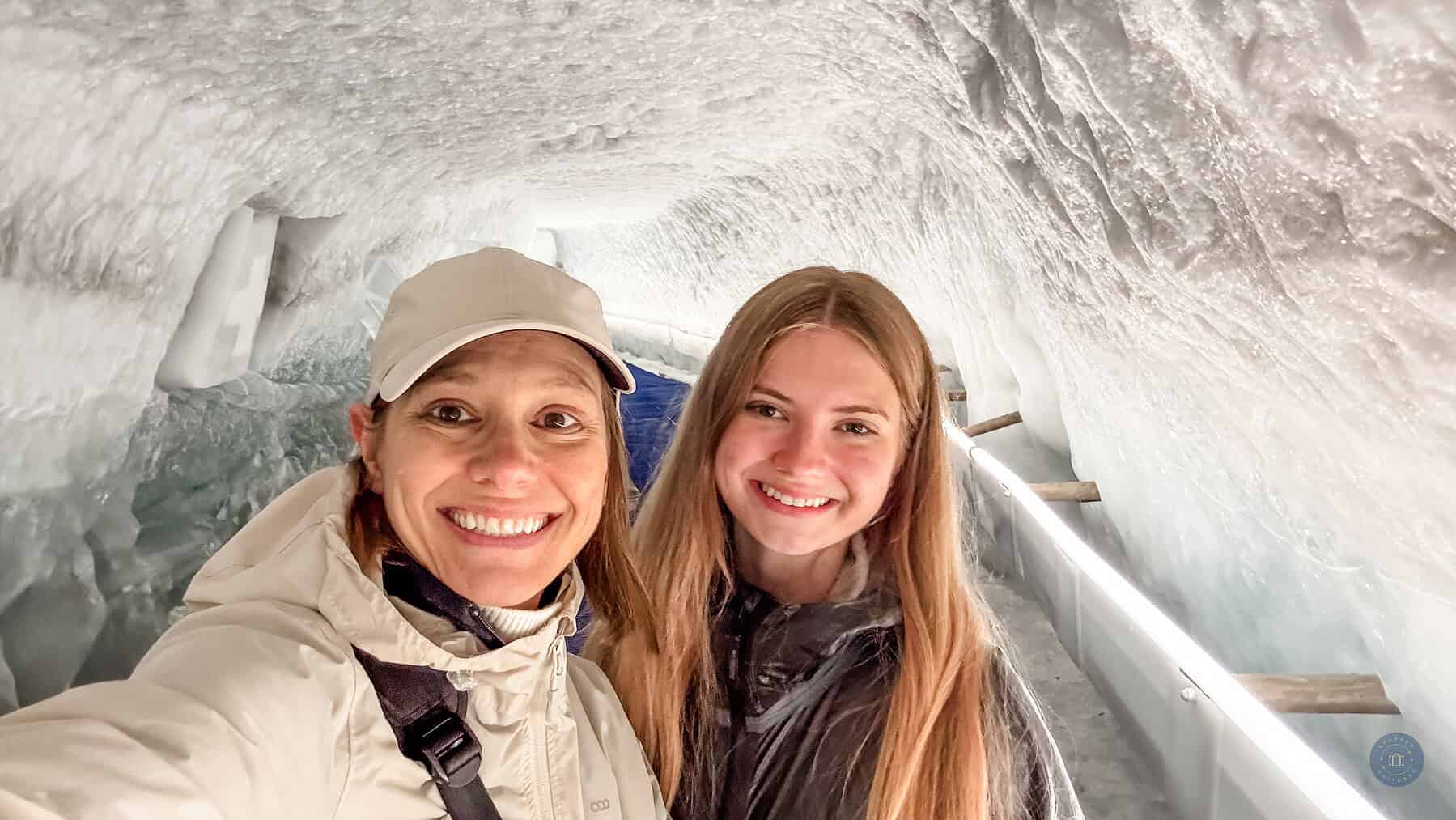 Mother and daughter exploring snow cave icy tunnels at Glacier Paradise Gondola near Zermatt Switzerland