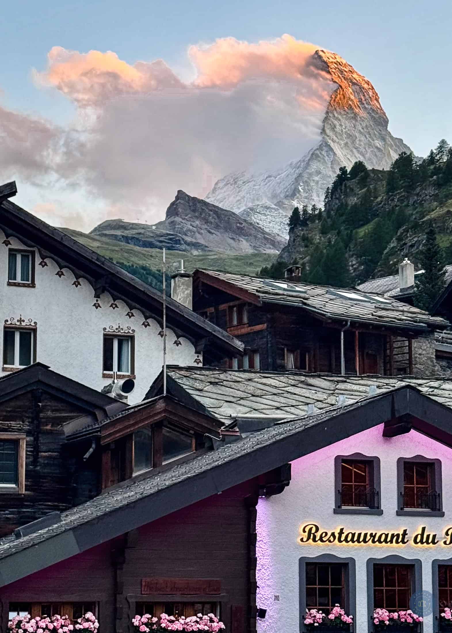 Colorful mountain village  of Zermatt with alpine architecture in Switzerland, snow-capped peak of Matterhorn at sunset in the background.