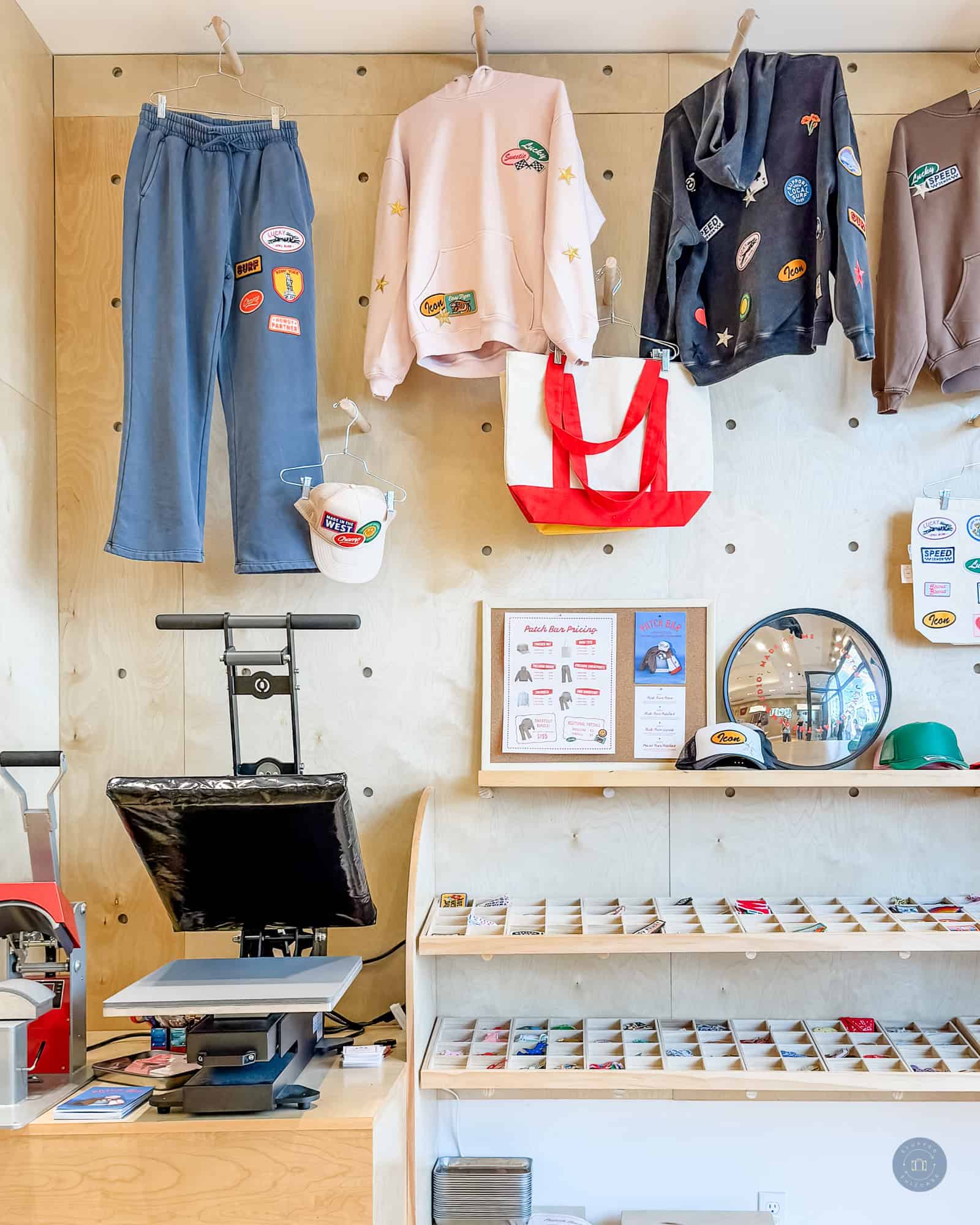 bags and clothes hanging on wall with patches and heat press at gem studio craft store in irvine spectrum center mall