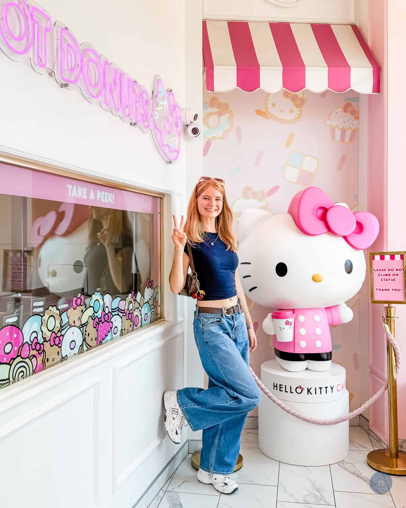 person standing in front of hello kitty statue in hello kitty cafe at irvine spectrum center