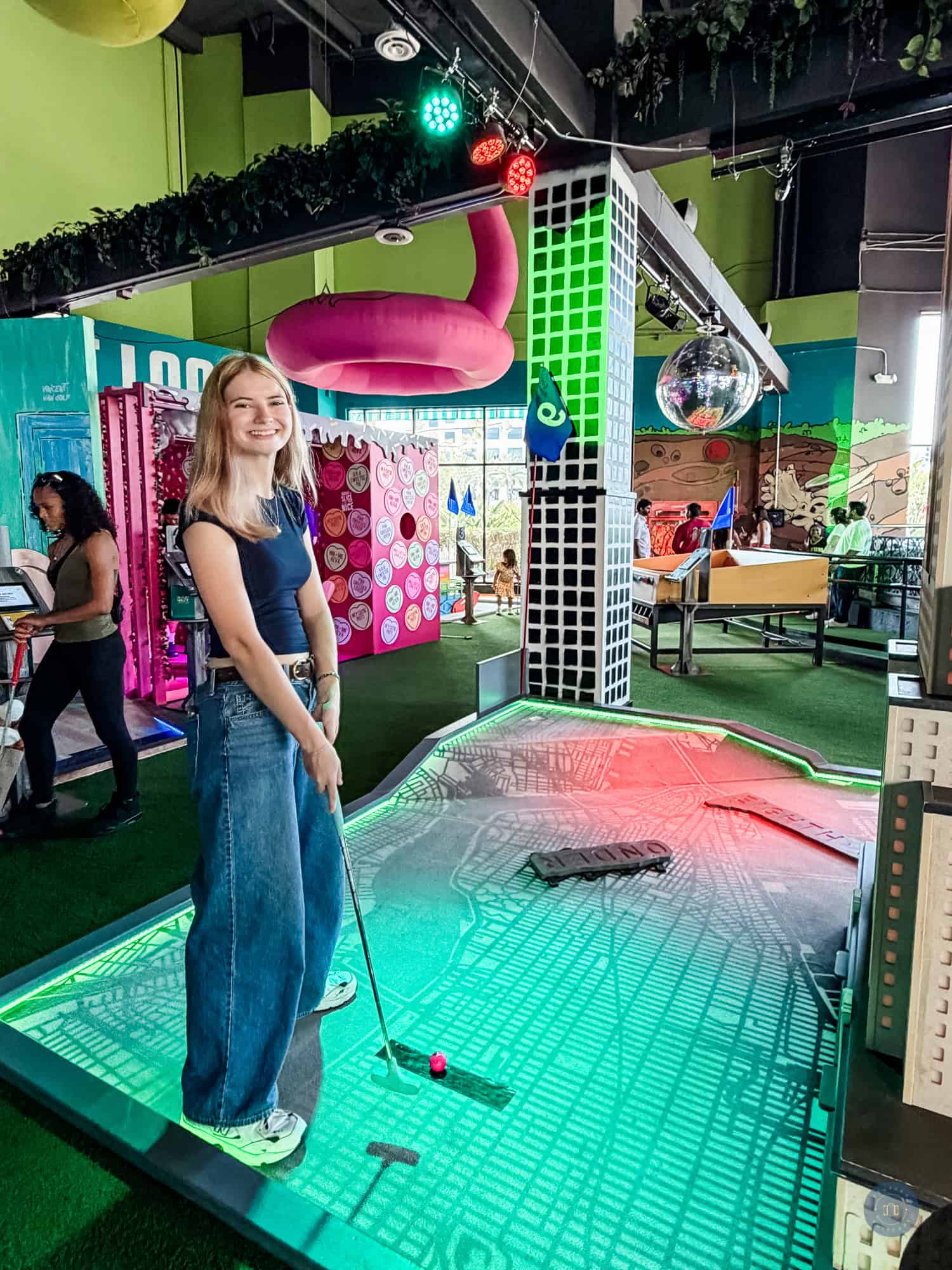 Teen girl playing mini golf at indoor center holey moley in Irvine.