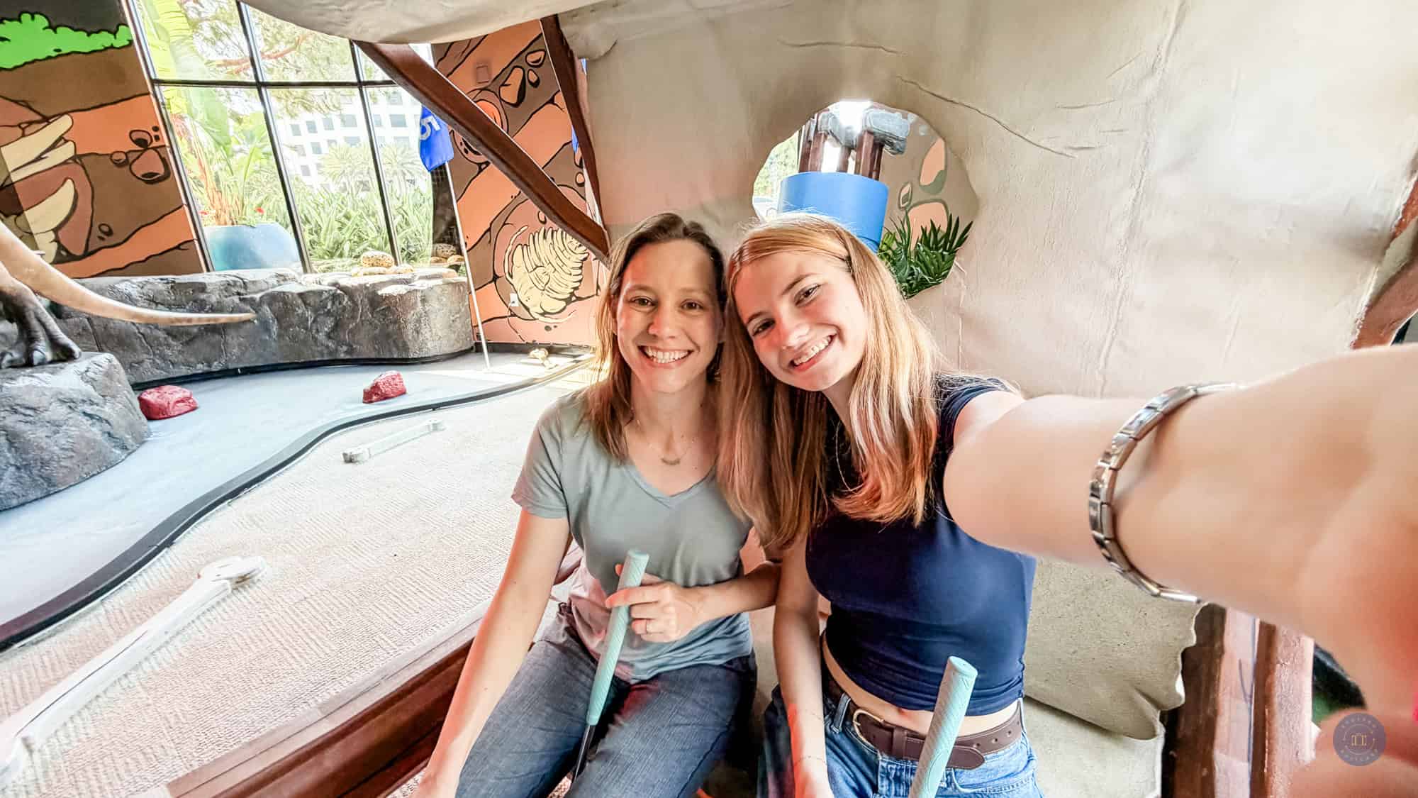 photo of mother and daughter in faux flinstones car on course at holey moley mini golf in irvine california
