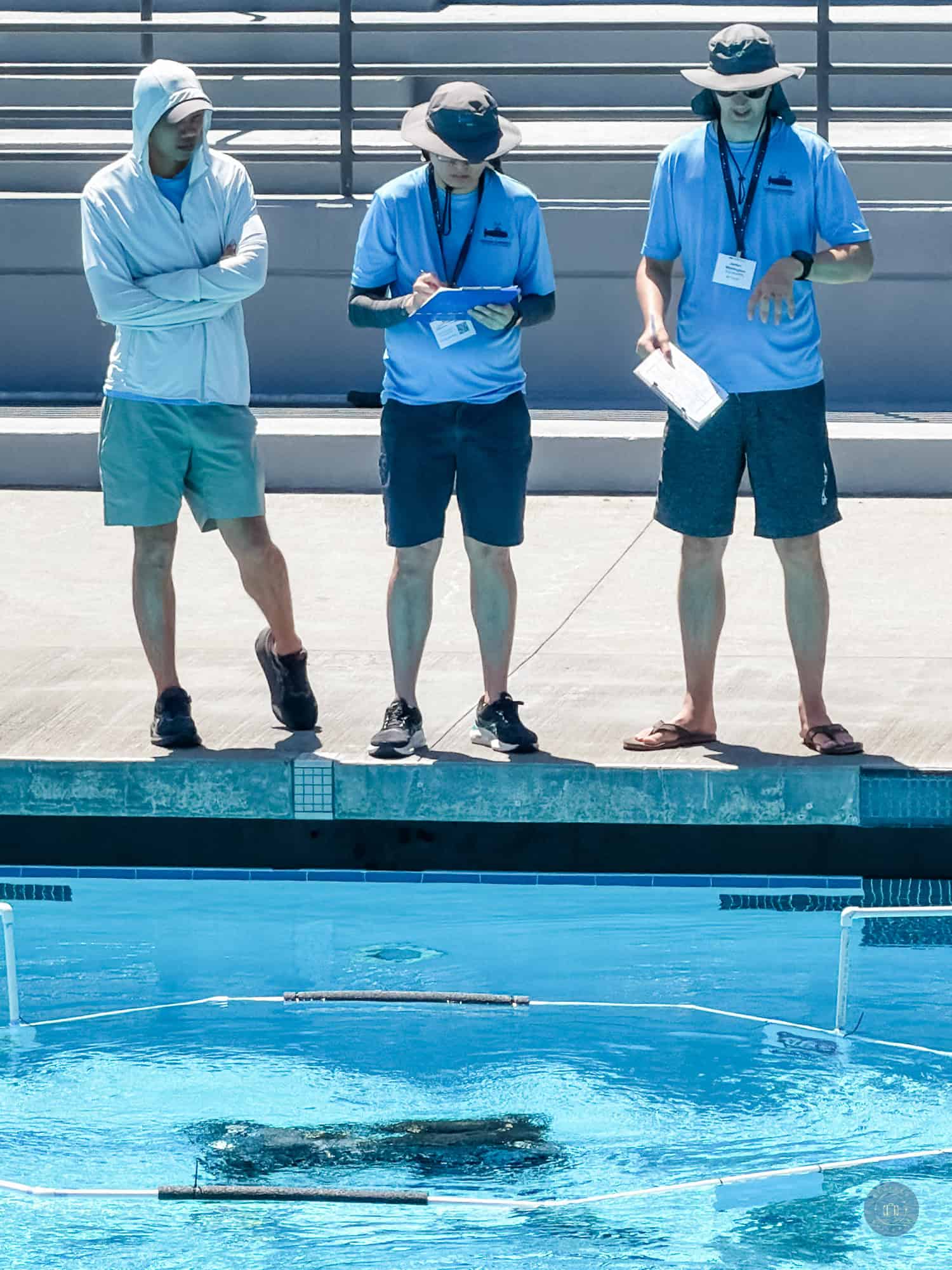 robosub competition judges and competitor at side of pool looking at robot underwater